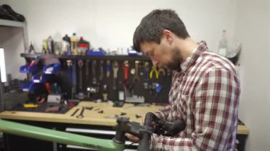 Bisiklet tamircisi atölyedeki bisiklet gidonu şeridini değiştiriyor. Bisiklet tamiri ve hizmet kavramı. Bisiklet teknisyeni gidona bant yapıştırıyor. Tamircide çalışan bisiklet tamircisi.. 