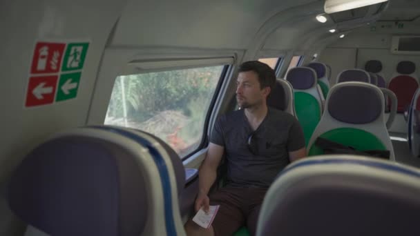Młody Człowiek Podróżujący Pustym Włoskim Pociągiem Kolorowymi Fotelami Korzystając Smartfona — Wideo stockowe