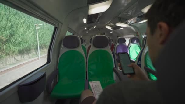 Молодой Человек Путешествует Пустом Итальянском Поезде Красочными Креслами Используя Свой — стоковое видео