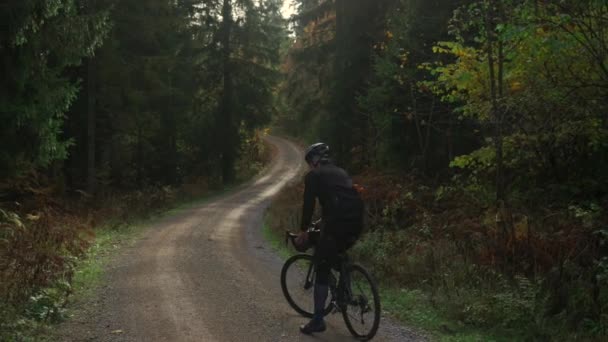バイエルン地域のドイツの山々にある黄色い葉を持つ森林の背後からの砂利の自転車の景色を乗馬する男性のサイクリスト 森の山岳地帯のビキパッカー自転車の秋 — ストック動画