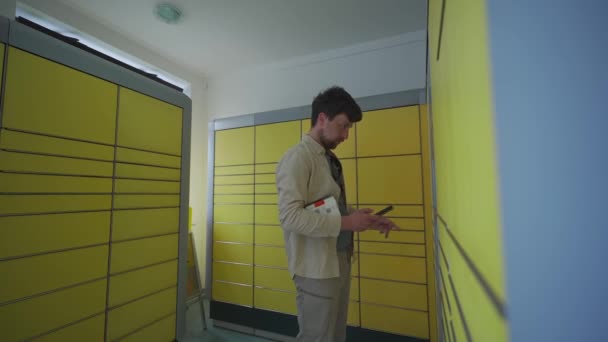 男はセルフサービスでパッケージを送信するために黄色の梱包ステーションを使用しています ドイツ語のパッケージと配送サービスターミナル 送信者の種類ドイツの黄色の梱包センターでラベルを追跡し パケットを送信 — ストック動画