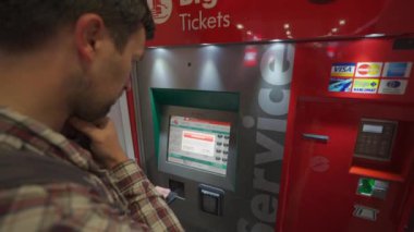 7 Ekim 2023. Roma. İtalya. Roma Fiumicino Havaalanı 'ndaki kırmızı renkli tren istasyonunun self-servis bilet makinesinden bilet alan bir adam. Trenitalia otomatik bilet otomatı. Bilet büfesi. 