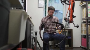 Erkek bisiklet tamircisi atölyede çalışıyor. Tamircide bisiklet bisikletinin lastiğini değiştiren bir tamirci. Bisiklet teknisyeni yeni lastik ve tüp takıyor. Çalışma İstasyonu. 