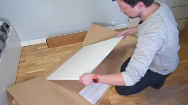 Homem Desempacota Caixa Móveis Desmontados Para Auto Montagem Com Faca — Vídeo de Stock