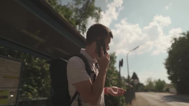 Man Controleert Tijd Polshorloge Afwachting Van Bus Bij Halte Oproepen — Stockvideo