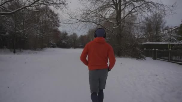 Mężczyzna Jogger Działa Śniegu Zimie Pomarańczowej Bluzie Widok Tyłu Ludzie — Wideo stockowe