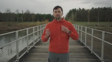 Erkek koşucu, açık hava koşusundan önce telli kulaklık takıyor. Koşucu, koşma sırasında müzik dinlemek için kulaklık takarak koşuya hazırlanır. Müzikle koşmak. 