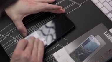 20 Kasım 2023. Münih. Almanya. Adam, Iphone 15 PRO için kentsel zırh teçhizatı GLASS PROTECTOR SHIELD PLUS 'u kuruyor. UAG Glass Shield Plus Premium ekran koruyucuları. Koruyucu cam takılıyor. 