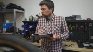 Bisiklet teknisyeni idari işler yapıyor. Motosiklet tamircisi iş belgelerini notlar. Bisiklet mühendisi iş başında. Araç tamircisi kayıtları atölyedeki panoda çalışıyor. Kalite kontrol süreci. 