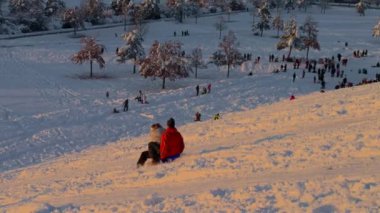 3 Aralık 2023. Münih, Almanya, Riemer Park, Messestadt. Riem parkındaki Toboggan tepesi ve gözlem güvertesi tepesi. Güneşli kış havasında Münih 'te bir parkta karlı dağda kayak yapan mutlu insanlar.. 