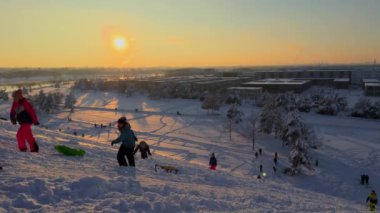3 Aralık 2023. Münih, Almanya, Riemer Park, Messestadt. Riem parkındaki Toboggan tepesi ve gözlem güvertesi tepesi. Güneşli kış havasında Münih 'te bir parkta karlı dağda kayak yapan mutlu insanlar.. 
