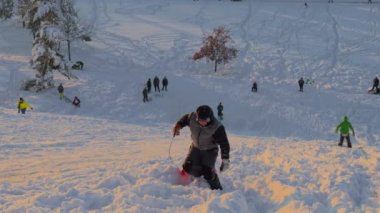 3 Aralık 2023. Münih, Almanya, Riemer Park, Messestadt. Riem parkındaki Toboggan tepesi ve gözlem güvertesi tepesi. Güneşli kış havasında Münih 'te bir parkta karlı dağda kayak yapan mutlu insanlar.. 