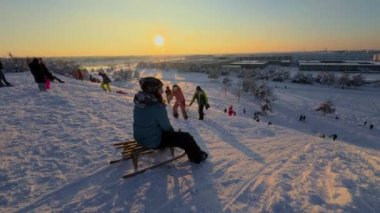 3 Aralık 2023. Münih, Almanya, Riemer Park, Messestadt. Riem parkındaki Toboggan tepesi ve gözlem güvertesi tepesi. Güneşli kış havasında Münih 'te bir parkta karlı dağda kayak yapan mutlu insanlar.. 