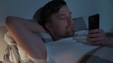Adam ciddi bir şekilde konsantre olmuş sohbet ediyor, mesaj yazıyor, yatakta cep telefonlarına bakıyor, geceleri derin uykular yerine yatak odasına bakıyor. Sosyal medya bağımlılığı. Uyku bozukluğu, uyku bozukluğu.