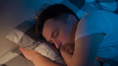 Genç bir adam gece yatağında uyanır ve yorgun bir bakışla gözlerini ovuşturur ve yastığın altından akıllı telefonu çıkarır. Erkek uyuya kalamaz ve telefonda zamanı kontrol edemez. Uyku problemleri, alet bağımlılığı 