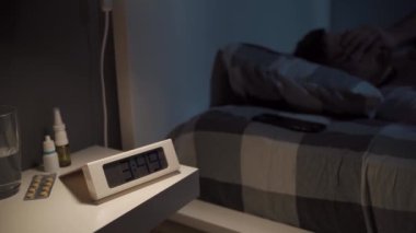 Stresli bir adam uyumaya çalışıyor. Elektronik saate odaklan. Uykusuz adam uykusuzluktan muzdarip. Karanlıkta gözleri açık, yatak konseptine uzanmış bir adam. Üzgün adam uykusuzluktan uyandı..