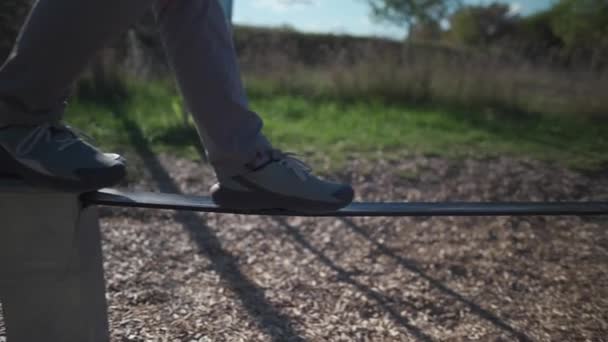 德国一名穿着鞋子的初学者在公园里学习走路 并在橡胶松驰线上保持平衡 在慕尼黑的城市体育馆里 男人们靠拉长的绳子保持平衡 松紧带 平衡橡胶绳 — 图库视频影像