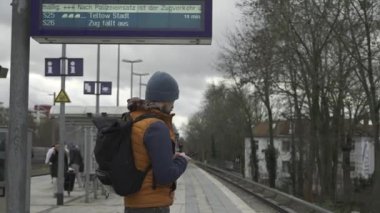 Almanya 'daki tren iptalleri. Berlin, Almanya 'daki banliyö tren istasyonunda uzun süre rötar yapmayı bekleyen bir adam var. Zug fallt aus, Deutschland. Almanya 'da demiryolu gecikmeleri. Şehir vatandaşı. 