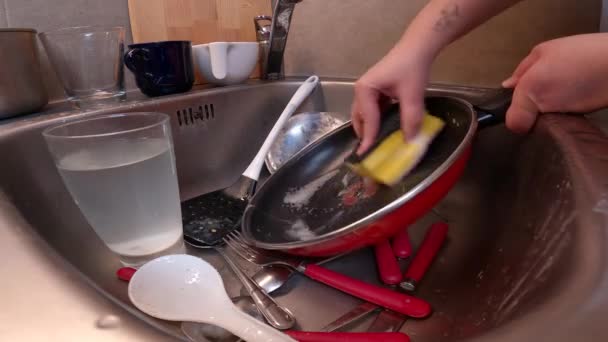家务活和洗碗 无法辨认的女人用海绵和洗涤剂在满满的盘子里洗平底锅 厨房的家务活和清洁 — 图库视频影像