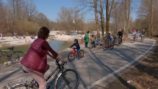 2022年3月22日 ミュンヘン ドイツ サイクリストは ムンヘンの晴れた暖かい天気で春のイザール川沿いのサイクルパスに乗ります ヨーロッパの町の川沿いの都市ツアーのサイクリスト アクティブレジャー — ストック動画