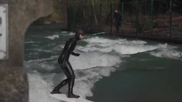 2022年3月25日 德国慕尼黑 在春天阳光明媚的天气里 冲浪运动员们在英式花园的伊萨克河上冲浪 人们观看着 爱斯巴赫河畔冲浪 Eisbachwelle Naquischen Garten Surf — 图库视频影像