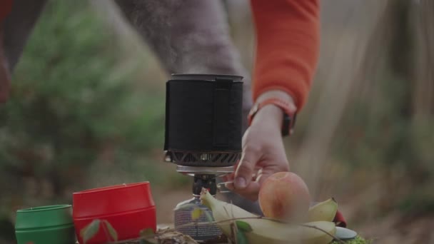 バックパッカーは秋のバックパッキング旅行中に切り株の森の中のガス燃料カートリッジに統合されたシステムポットとバーナーでお茶を調理します ハイカーはポータブルガスストーブで熱い飲み物を準備します — ストック動画