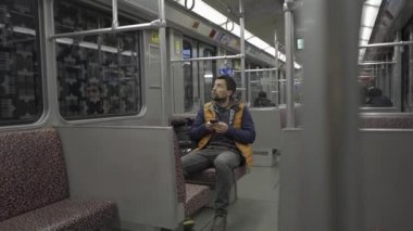 Adam Berlin, Almanya 'da metroya biniyor ve akıllı telefon kullanıyor. Banliyö treninde akıllı telefonu olan bir erkek. Berlin metrosunda internette internette sörf yapan bir yolcu. Fahrgast in der U-Bahn in Berlin, Deutschland. 