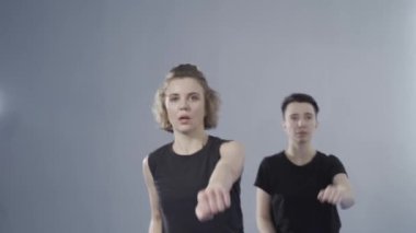 Dövüş sanatları dersi için çift antrenmanı. İki bayan koç ve tekvando teknikleri üzerinde çalışan bir öğrenci. Karatedeki iki kadın dövüşçünün kol darbeleri. Kadınlar için kişisel savunma. 