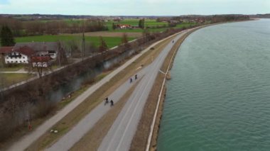 Bisikletçiler, Almanya 'nın Bavyera eyaletinde Rosenheim nehri boyunca bisiklet yolu üzerinde bisiklet sürerler. Ben Innradweg bei Rosenheim. Deutschland 'da geniş bir nehir boyunca çakıllı bisiklet yolu. Üst Bayern 'de döngü. 