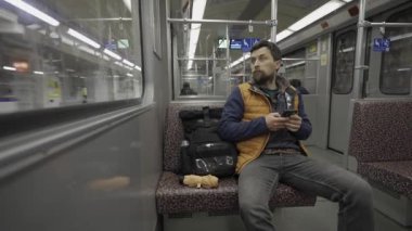 Adam Berlin, Almanya 'da metroya biniyor ve akıllı telefon kullanıyor. Banliyö treninde akıllı telefonu olan bir erkek. Berlin metrosunda internette internette sörf yapan bir yolcu. Fahrgast in der U-Bahn in Berlin, Deutschland. 