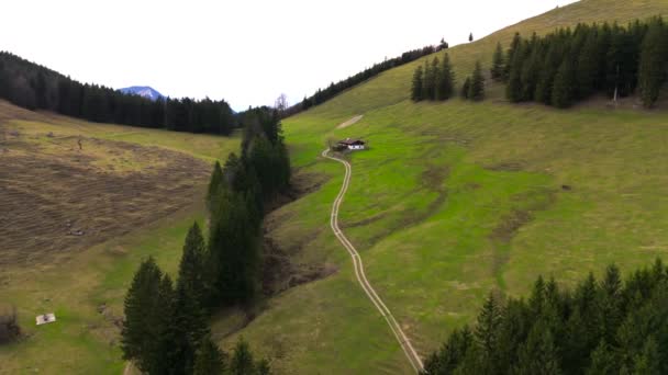 伝統的なドイツの家は バイエルンアルプスにそれにつながる道路と山に立っています 未舗装の道路を持つ高山の観光客のための単一の小屋 ドイツの丘と農家の空中観察 — ストック動画