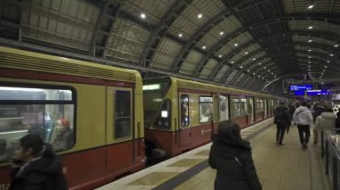 25 Aralık 2023. Berlin, Almanya. Akşamları Alexanderplatz 'da. Berlin şehir merkezindeki tren istasyonu, Almanya. Bahn Alexanderplatz yolcuları sarı banliyö treniyle gelir ve gider.. 
