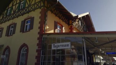 1 Mart 2024. Tegernsee, Almanya. Bahnhof Tegernsee im oberbayerischen Landkreis Miesbach. Güneşli havada Bavyera Alpleri 'ndeki tren istasyonu. Turşular, tren istasyonunda bir sürü insan trenden indi.. 