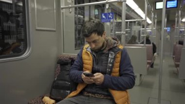 Adam Berlin, Almanya 'da metroya biniyor ve akıllı telefon kullanıyor. Banliyö treninde akıllı telefonu olan bir erkek. Berlin metrosunda internette internette sörf yapan bir yolcu. Fahrgast in der U-Bahn in Berlin, Deutschland. 