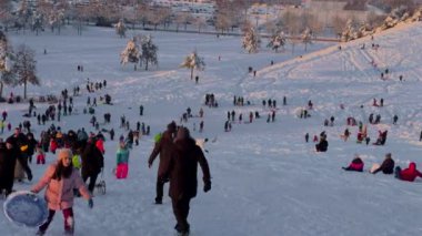 3 Aralık 2023. Münih, Almanya, Riemer Park, Messestadt. Riem parkındaki Toboggan tepesi ve gözlem güvertesi tepesi. Güneşli kış havasında Münih 'te bir parkta karlı dağda kayak yapan mutlu insanlar.. 