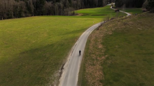 バイエルンアルプスの山岳渓谷のアスファルト道路に乗り ドイツの雪に覆われた山々を眺める ドローンからの眺め アルペンロードを走る空中ビュー自転車 — ストック動画