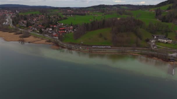 ドイツのバイエルン上部のテガネーゼ湖に沿って列車が走ります 美しいバイエルン湖に沿った鉄道トラックのドローンビュー ドイツの鉄道輸送について アイゼンバーン — ストック動画