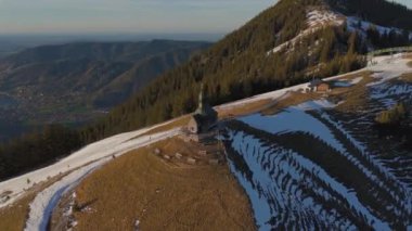 Kapelle Heilig Kreuz Rottach-Egern Tegernsee. Wallbergkapelle, Tegernsee Gölü 'ne tepeden bakan Wallberg Dağı ve güneşli bahar havasında gün batımında karla kaplı dağ sıraları. Alplerin zirvesindeki şapel. 