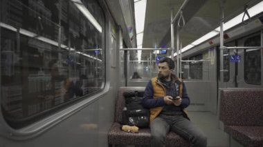 Adam Berlin, Almanya 'da metroya biniyor ve akıllı telefon kullanıyor. Banliyö treninde akıllı telefonu olan bir erkek. Berlin metrosunda internette internette sörf yapan bir yolcu. Fahrgast in der U-Bahn in Berlin, Deutschland. 