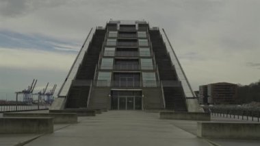 Hamburg, Almanya. Hamburg 'daki modern mimari Dockland ofis binası. Ziyaretçiler için merdiven erişimi olan rıhtım binası ve Elbe Nehri 'nin liman ve kıyısının manzarası. 