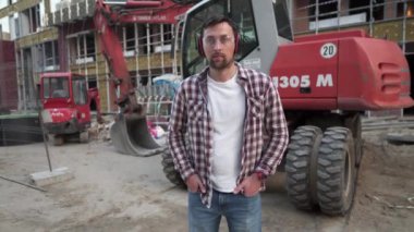 İnşaat alanında buldozer kullanan bir işçi. Erkek kazıcı işçi. İnşaat mühendisi işçi operatörü ve arka planda kazıcı var. Toprak hareket eden bir makine ya da bir binanın önünde dozer taşıyan bir çalışan.. 