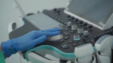 Doktorların yakın çekimleri klinikte teşhis sırasında ultrason cihazına koruyucu lateks eldiven takıyor. Steril eldivenli doktor, muayene sırasında ultrason tarayıcısı kullanıyor. USG makinesi. 