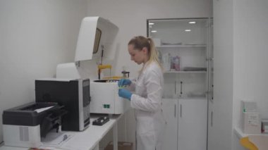 Üniformalı laboratuar teknisyeni kan örneklerini otomatikleştirilmiş robot makineye yerleştiriyor. Biyolojik sıvıların analizi için klinik kimya çözümleyicisi numunelerin incelenmesi için tıbbi laboratuvar ekipmanları için.. 