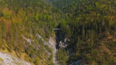 Luftaufnahme Schurpfen Wasserfall. Eğri şelale Schurpfen 'in hava manzarası ve Lenggries' deki Sylvensteinspeicher yakınlarında orman dağı ve kanyonla dolu bir köprü. İnsansız hava aracı görüntüsü düşüyor ve köprü. 