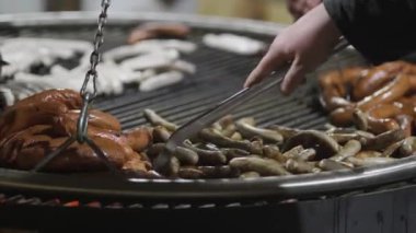 Şeflerin elleri kışın Almanya 'da Noel pazarında ateşte asılı duran metal ızgarada sosis pişiriyor. Akşamları Noel Fuarı 'nda farklı türde sosisli barbekü. Bayerische Wurste. 