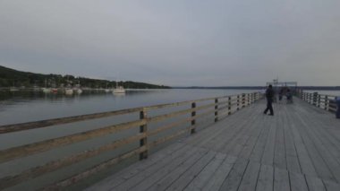 20 Mayıs 2024 Herrsching am Ammersee, Bavyera, Almanya. İnsanlar Ammersee Gölü 'nün avlusunda kafelerde ve restoranlarda rahatlarken, aynı zamanda su boyunca ve yazın günbatımında ahşap iskelede yürüyorlar.. 