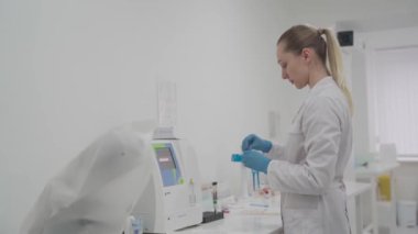 Kadın laboratuvar teknisyeni hematoloji kan analizcisi kullanıyor. Laboratuvarda tıbbi malzemeler. Biyokimyasal ve kan analizi. Tıbbi laboratuvarda otomatik kan testi analizcisi