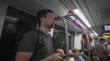 İtalya 'da Roma metrosundaki erkek yolcu yazın kalabalık bir metro treninde akıllı telefon kullanıyor. Erkek, Roma 'da tren vagonunda seyahat ederken telefon kullanıyor. Roma 'da toplu taşıma teması