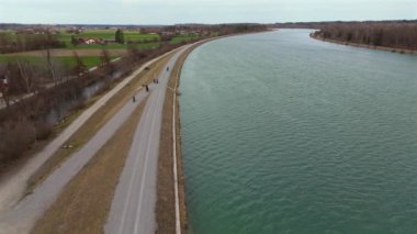 Bisikletçiler, Almanya 'nın Bavyera eyaletinde Rosenheim nehri boyunca bisiklet yolu üzerinde bisiklet sürerler. Ben Innradweg bei Rosenheim. Deutschland 'da geniş bir nehir boyunca çakıllı bisiklet yolu. Üst Bayern 'de döngü. 