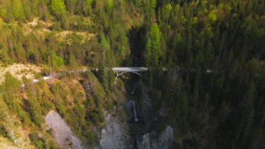 Luftaufnahme Schurpfen Wasserfall. Eğri şelale Schurpfen 'in hava manzarası ve Lenggries' deki Sylvensteinspeicher yakınlarında orman dağı ve kanyonla dolu bir köprü. İnsansız hava aracı görüntüsü düşüyor ve köprü. 